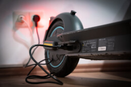 An e-scooter plugged into the wall for charging